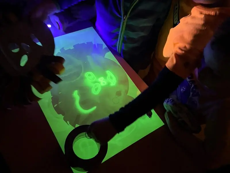 Kinder malen mit fluoreszierenden Farben unter UV-Licht